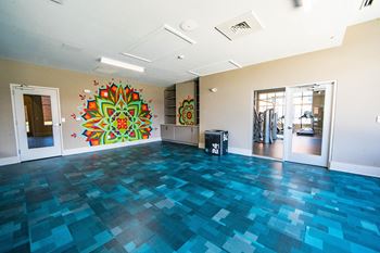 A room with a blue tiled floor and a large mandala painting on the wall.